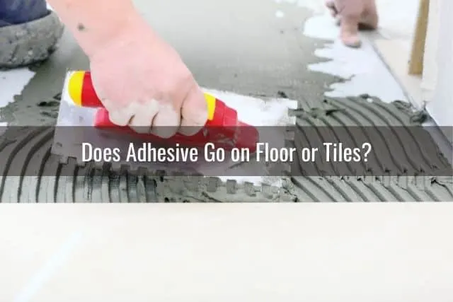 Hand with trowel applying floor adhesive