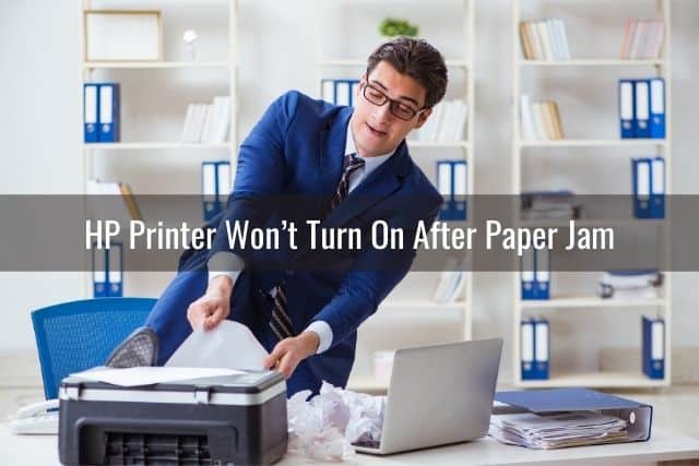 Businessman pulling paper jam out of printer