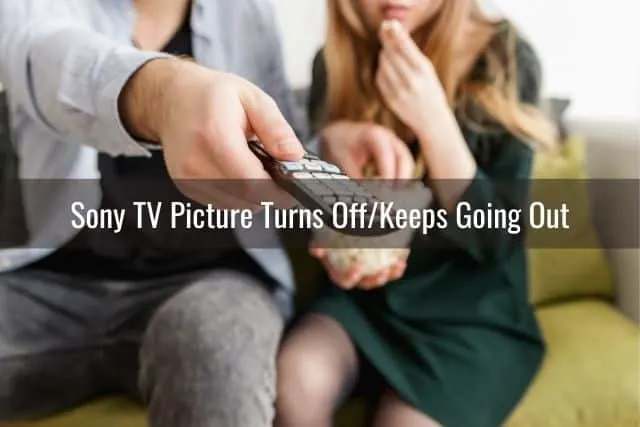 A couple sitting on a sofa with man changing TV channel with remote