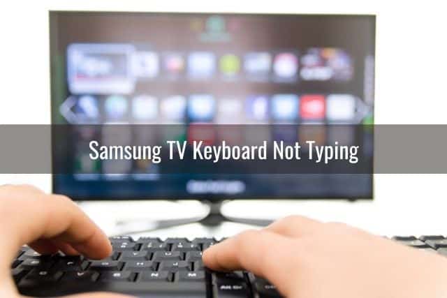 Closeup of hand typing on keyboard with Smart TV in the background