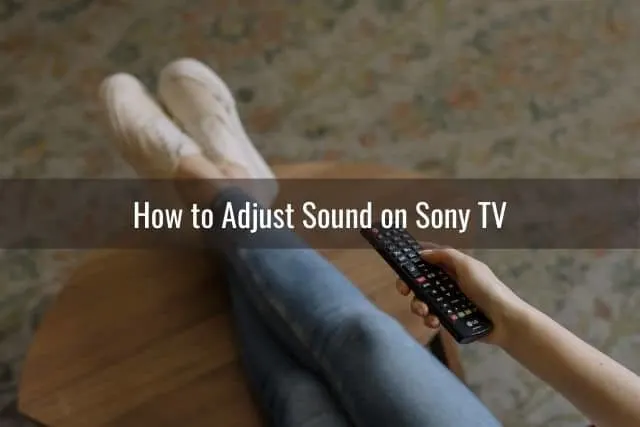 Girl with jeans sitting on ground holding TV remote