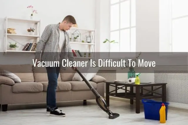 Guy in jeans vacuuming carpet in living room