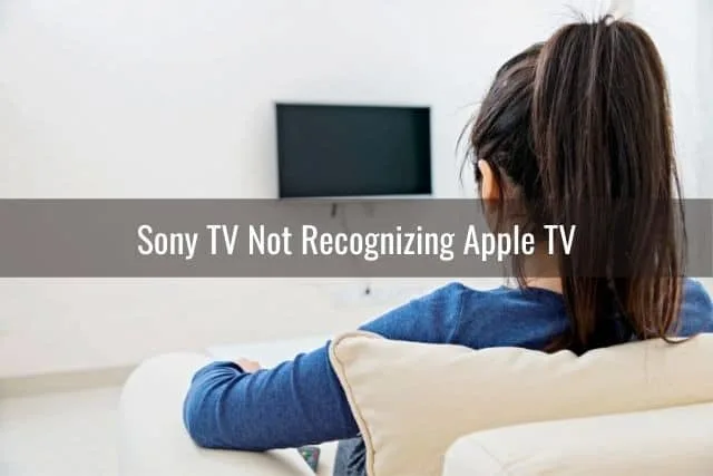 Female sitting on sofa and starring at TV that is turned off