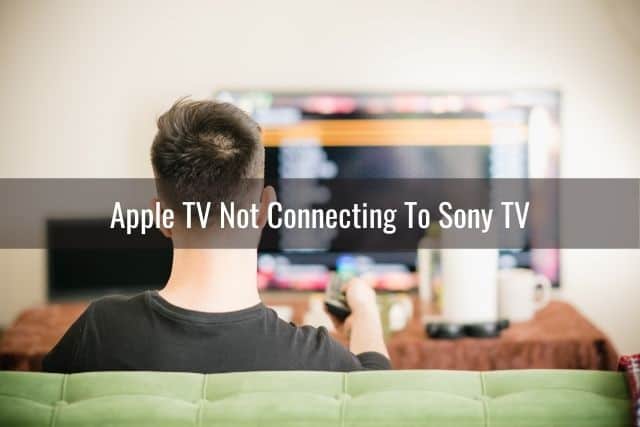 Guy sitting on sofa using remote to change TV channels