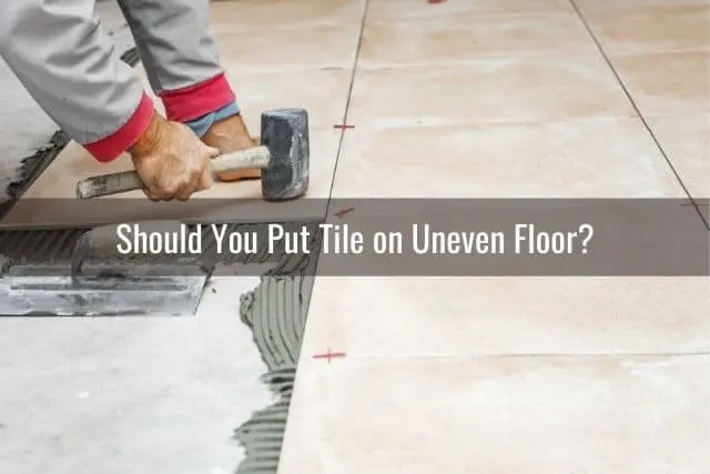 Man installing tile flooring with mortar and hammer