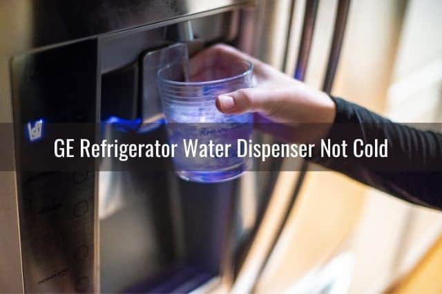 Hand holding cup under refrigerator water dispenser