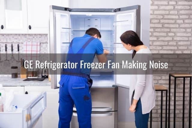 Repairman fixing refrigerator with female standing and watching
