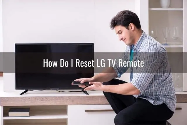 Man kneeling and looking at the TV remote in his hand