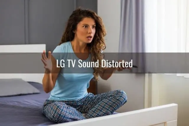 Female sitting on bed with a TV remote in hand and looking confused