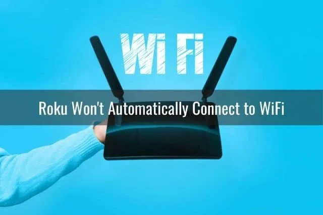 Hand holding WiFi router against blue background