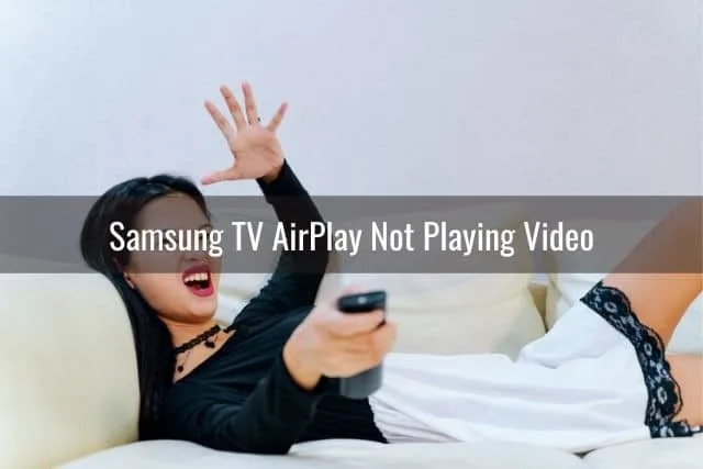 Asian female lying on sofa with hand up in the air frustrated while watching TV