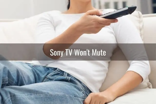 Woman sitting on sofa changing TV channels with remote
