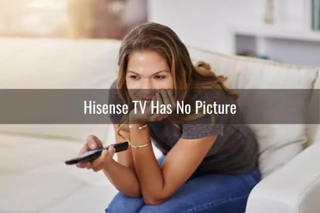 Female sitting on sofa using remote while watching TV