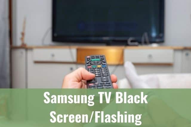 Hand holding TV remote and pointing it at the screen to turn on