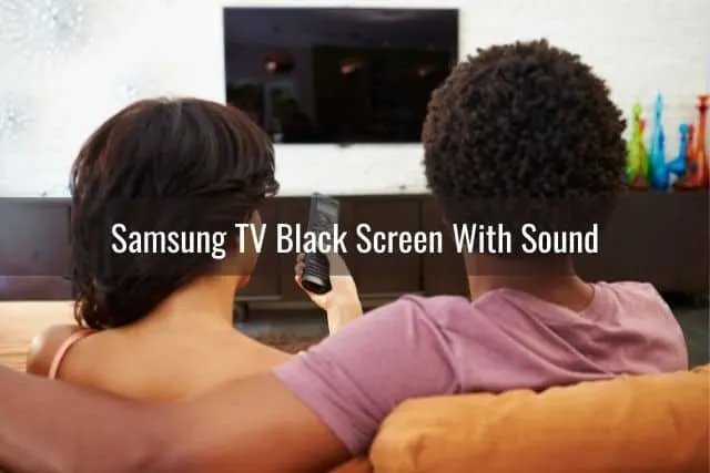 Couple sitting on sofa with female about to use remote to turn TV on