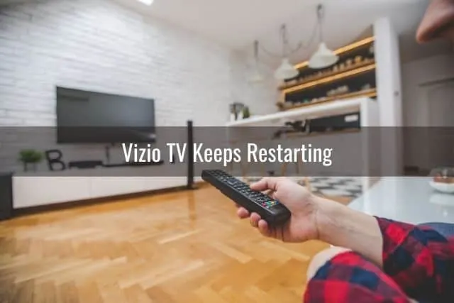 Hand using remote to turn on wall mounted TV