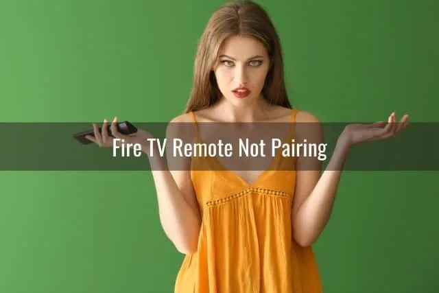 Confused female with hands up and TV remote in one hand