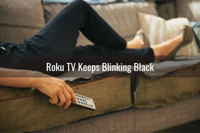 Person lying on couch watching TV with a remote in hand