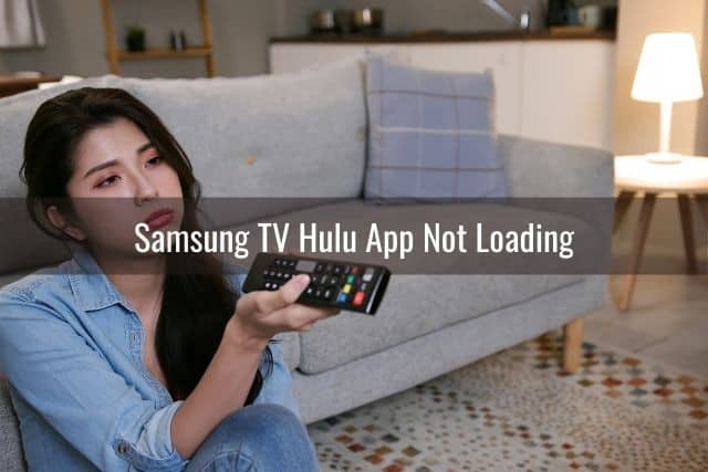 Bored female sitting on living room floor using remote to change TV programming
