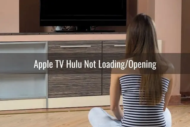 Young female sitting on ground trying to turn TV on