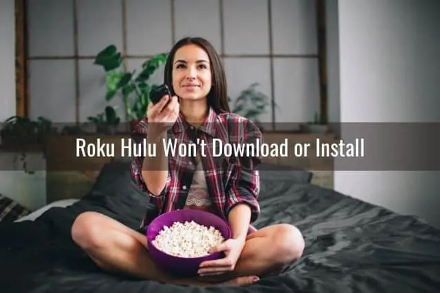 Female sitting on bed using TV remote and holding bowl of popcorn