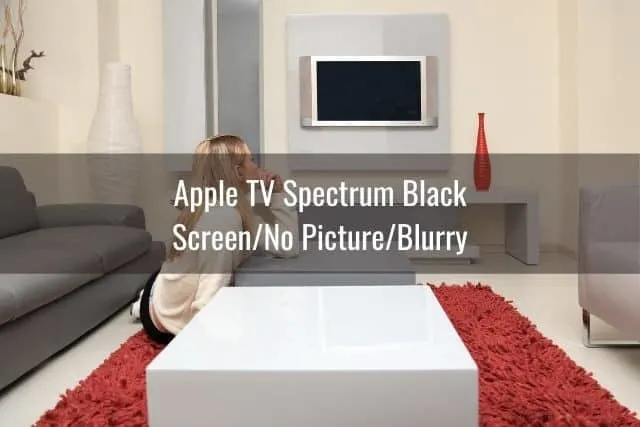 Female sitting on living room floor looking at wall mounted TV