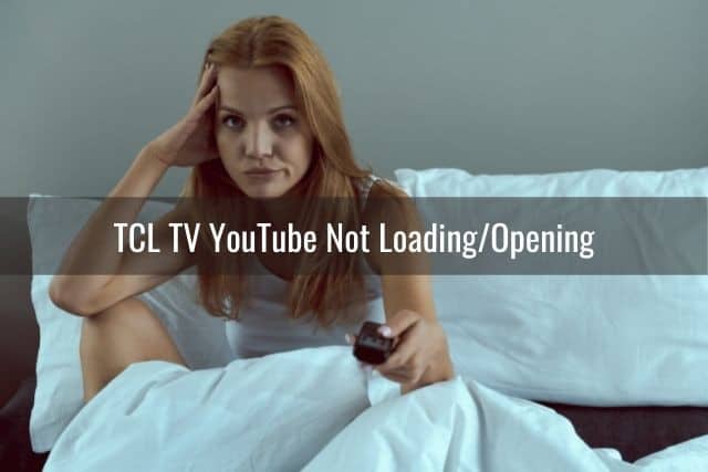 Annoyed female sitting in bed holding TV remote