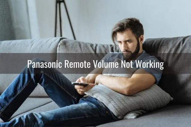 Sad man holding a remote while laying on the sofa