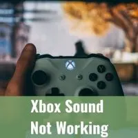 White Xbox controller held in front of TV