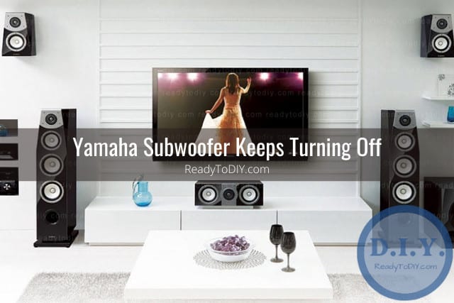 Black subwoofer on the floor and with flatscreen tv