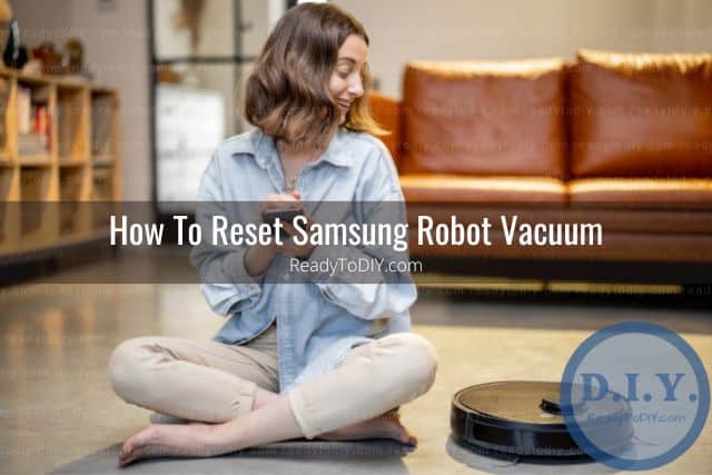 Female sitting on living room floor staring at robot vacuum next to her